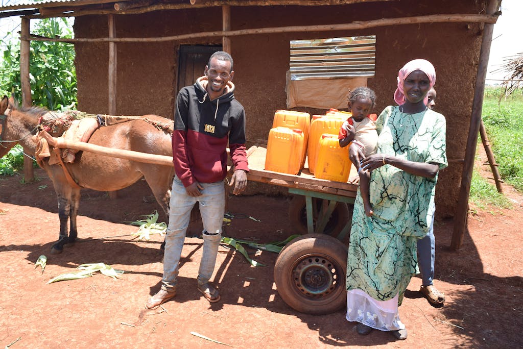 Aliyi and his family display the cart and water jugs it allows him to transport.