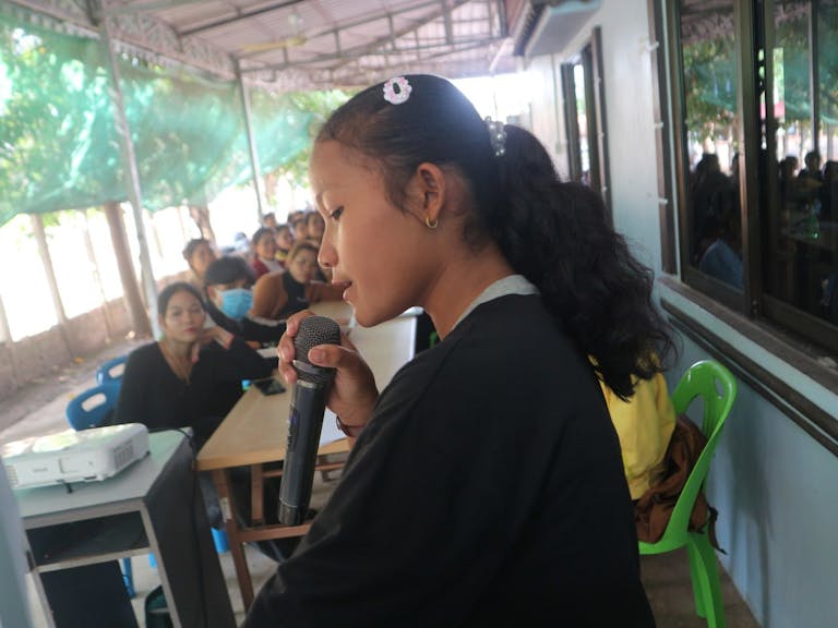 SreyMe speaking into a microphone and sharing with her community.