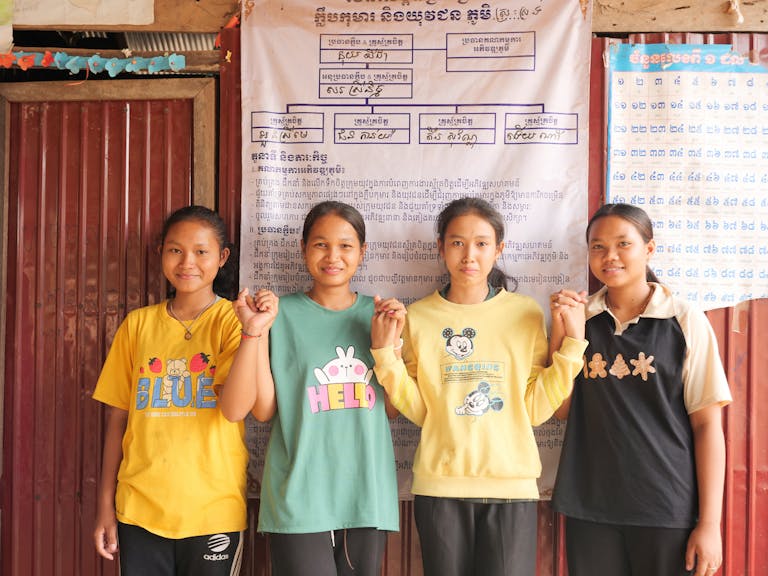 SreyMe and her peers, holding hands and smiling with pride in their accomplishments.