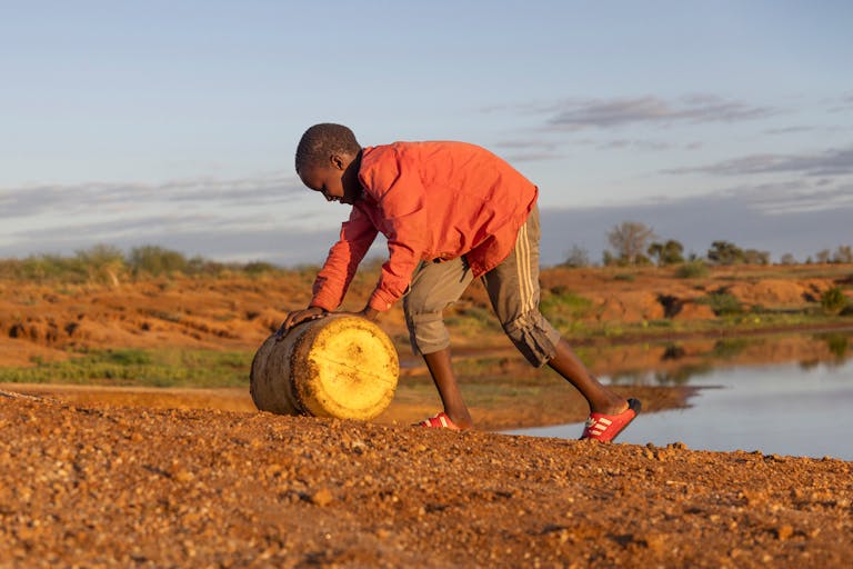 Adan works hard collecting water from the dangerous dam.